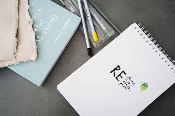 FAQs notebook on a countertop beside some paintbrushes and a journal